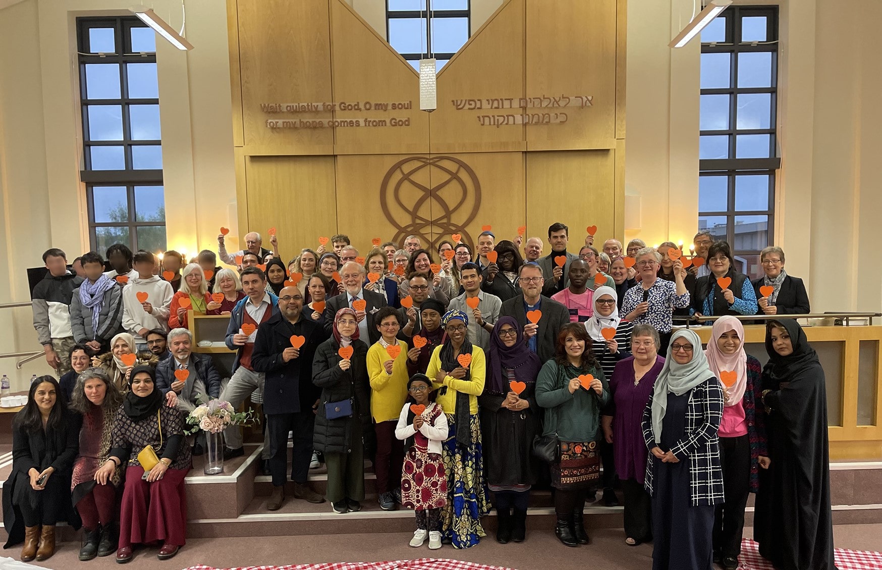 Members of three faiths gathering before Iftar in our synagogue, holding orange hearts, the symbol of refugee welcome Credit Kevin Snyder, United Reformed Church